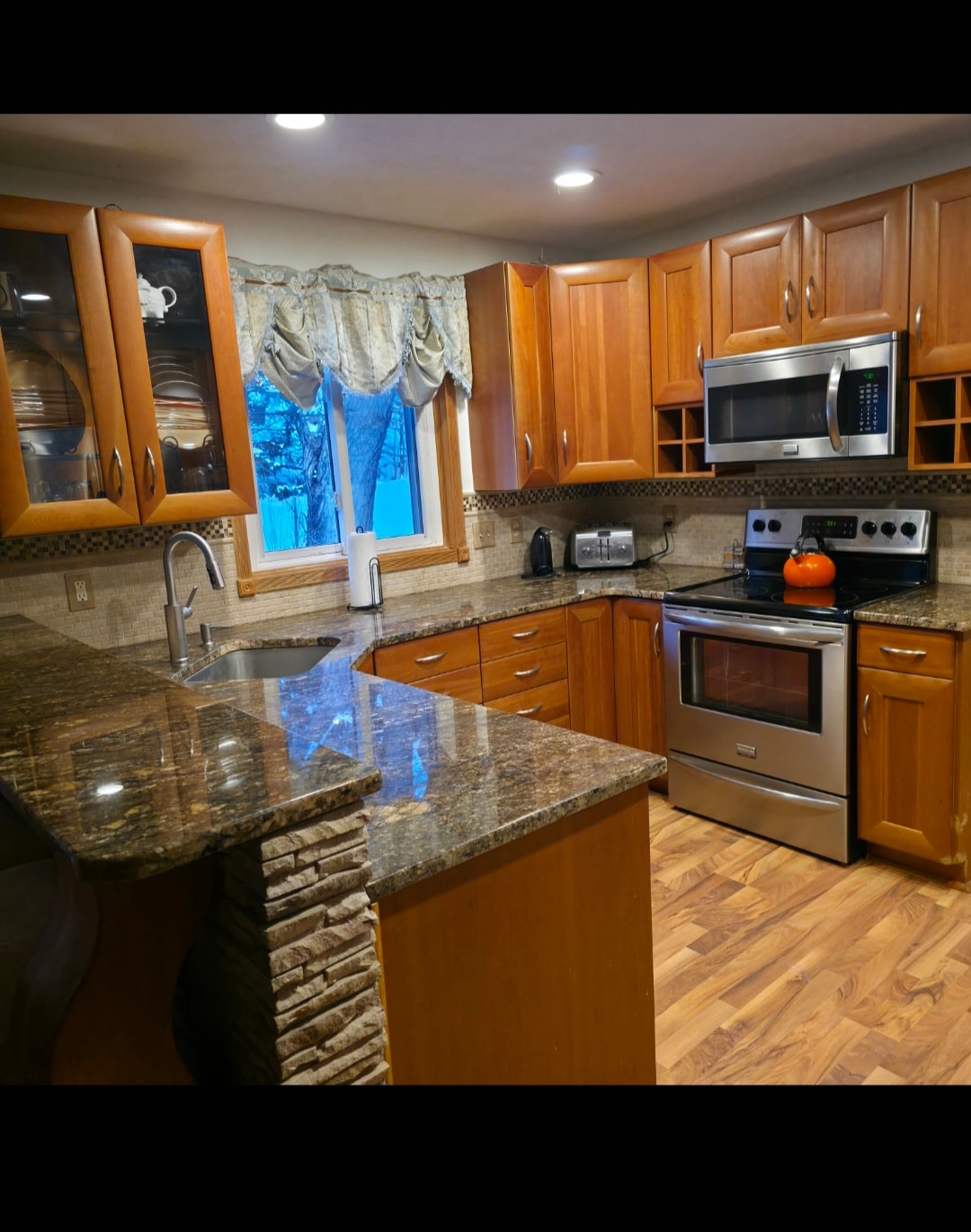 Modern kitchen with wood cabinets and granite countertops at Floxy AbilityNest